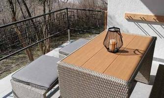 A cozy balcony with a rattan garden furniture set. A wooden table and a bench, decorated with a lantern.