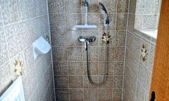 A modern shower with tiled walls and a showerhead. The space is bright and simply designed.