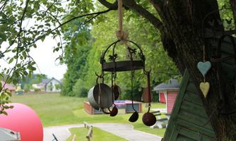 A decorative wind chime hangs from a tree. In the background, there is a green meadow and a toy landscape.