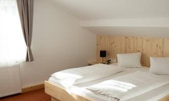 A bright bedroom with a spacious double bed and wood paneling. Large windows provide plenty of natural light.