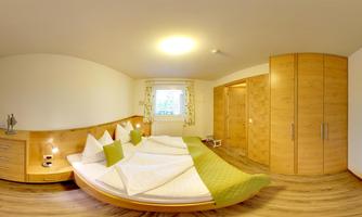 A cozy bedroom with a double bed and green accents. The walls are light, and there is plenty of storage with a large wardrobe.