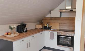 A modern kitchen with a wooden countertop and white cabinets. It is well-equipped and has a cozy atmosphere.