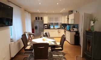 A modern kitchen with a dining area. The room is brightly lit and well-furnished.