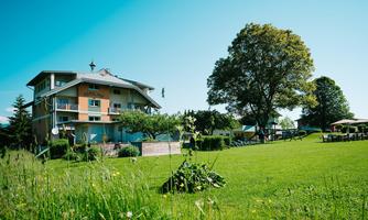 A modern building surrounded by green grass and trees. The sky is blue and clear, creating an inviting atmosphere.