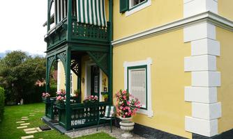 A charming house with a yellow paint and a balcony. The garden is well-maintained and decorated with flowers.