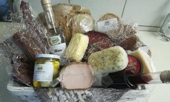 A basket with various foods, including bread, sausage, cheese, and vinegar. The ingredients are carefully packaged and provide a colorful selection of regional products.