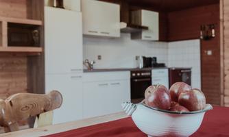 A modern kitchen with wooden cladding and white furniture. Fresh apples are in a bowl on the table.