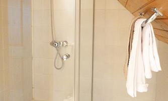 A modern shower with clean lines in a bright bathroom. Towels hang within reach on a hook.