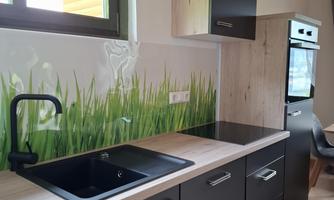 Modern kitchen with an elegant design in black and wood. The wall is adorned with a green grass decoration that adds a fresh accent.