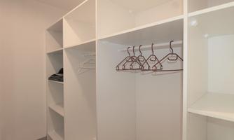 A bright wardrobe with white shelves and hangers. The room is well-organized and tidy.