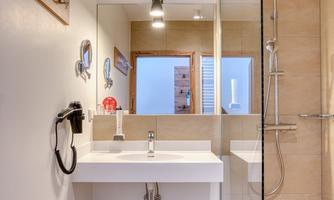 A modern bathroom with a clear shower and an elegant vanity. Towels are neatly placed on the shelf.