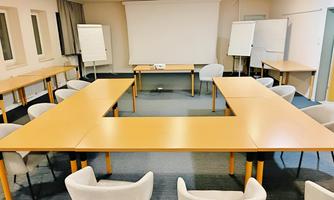 Our spacious 100 m² seminar room provides the perfect setting for meetings, workshops, and training sessions. It has been extensively upgraded with advanced lighting technology, a new floor, and comfortable chairs for a productive working environment. The room is equipped with a large screen, projector, and multiple flipcharts. The flexible table arrangement allows for a customized setup to suit various needs.