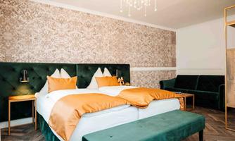 An elegant bedroom with a double bed and orange bedspreads. The walls are adorned with stylish wallpaper and the decor is modern.
