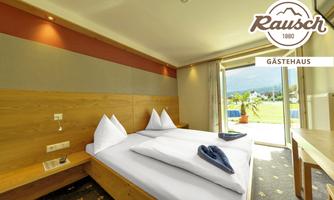 A modern guest room with a large double bed and soft colors. Large windows offer a view of the garden.