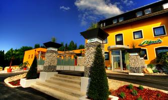An inviting hotel with a bright yellow facade and modern stone columns. The surroundings are well-kept with plants and a clear blue sky.