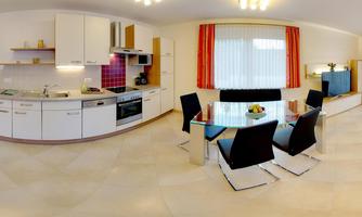 A modern kitchen with white cabinets and high-quality appliances. The dining area is furnished with a glass table and black chairs.