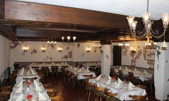 An inviting restaurant with wooden ceiling beams and elegant lighting. The tables are beautifully set and invite you to dine.