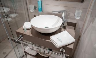 A modern bathroom with a round sink and stylish fixtures. Clean towels and toiletries are neatly arranged.