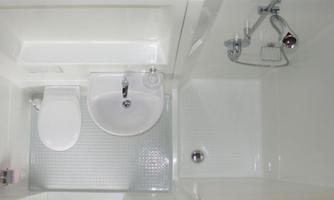 A modern bathroom with a toilet, a sink, and a shower. The furnishings are predominantly in white.
