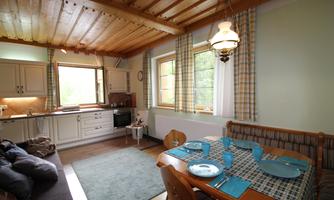 A cozy kitchen with a dining area and a large window. The table is nicely set with blue plates and an inviting atmosphere.