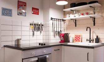 A modern kitchen with white cabinets and a black workspace. Kitchen utensils and decorative signs hang on the wall.