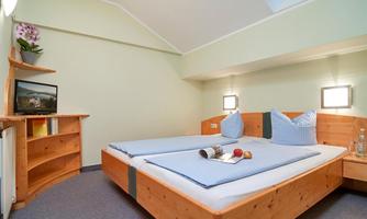 A cozy room with two beds, a television, and a wooden shelf. Apples and a magazine are on the table.