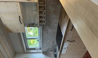 A modern kitchen with wooden shelves and a sink. Bright colors and plenty of light create an inviting atmosphere.