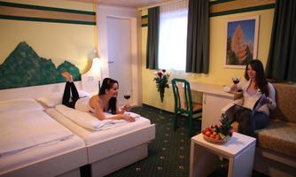 A cozy hotel room with two beds and a relaxed atmosphere. Two women enjoy wine and read in a pleasant environment.