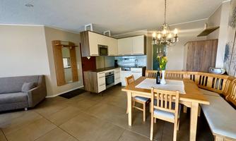 A modern kitchen with a dining table and chairs. The room also features a cozy seating area.