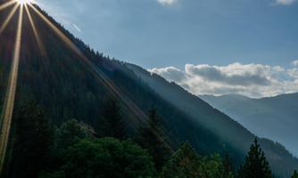 A beautiful mountain landscape with shining sunlight and wooded slopes. The atmosphere feels peaceful and clear.