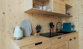 A modern kitchen with wooden paneling. On the countertop, there are kitchen appliances and utensils.