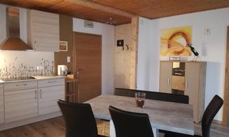 A modern kitchen with a dining area. The room is bright and comfortably furnished.