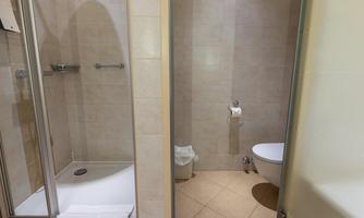 A modern bathroom with a shower and a toilet. The walls are brightly tiled and the floor is made of ceramic tiles.