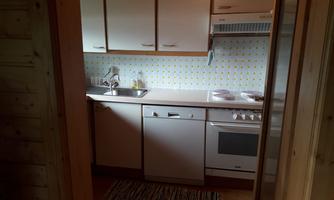 A cozy kitchen with white cabinets and modern features. The floor is decorated with a colorful runner.