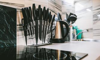 A modern kitchen with a knife block and a kettle. The elegant workspace is well-organized and clean.