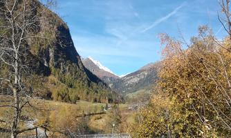 A beautiful mountain landscape with autumn colors. The snow-capped peaks rise majestically into the blue sky.