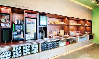 A modern café counter with various drinks and snacks. The shelves are neatly arranged and provide an inviting atmosphere.