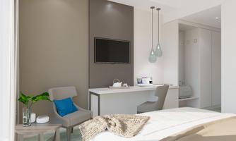 A modern room with a cozy bed and a small desk. The decor is bright and inviting, with an elegant seating area and plants.