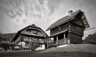 Two traditional wooden houses in a picturesque landscape. The sky is cloudy, giving the scene a nostalgic atmosphere.