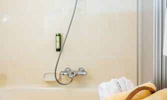 A modern bathroom with a bathtub and a shower. In the foreground, there is a basket with fresh towels.