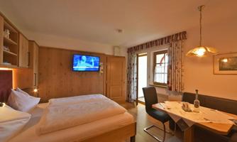 A cozy room with a double bed and a television. The dining area with table and chairs provides an inviting atmosphere.