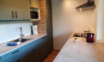 A modern kitchen with wood and gray tones. It features a sink, a stove, and various kitchen appliances.