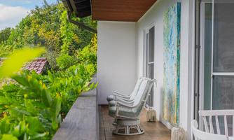 Covered balcony with cozy chairs and plenty of greenery – here you can wind down for the day with a coffee or a glass of wine.