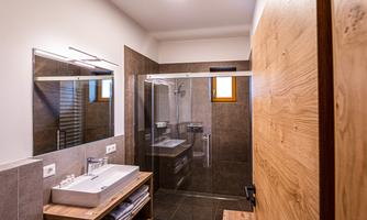 A modern bathroom with a clear shower cabin and a stylish sink. The walls are in neutral colors and there are wood details for a warm accent.