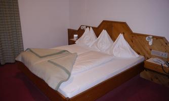 A cozy bedroom with a large double bed and two pillows. The room has a warm atmosphere and is simply furnished.