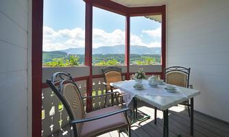 A cozy balcony with a view of the mountains. A table with tea set and chairs invites you to relax.
