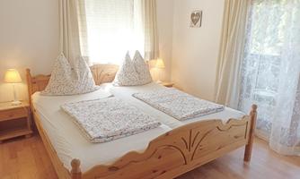 A cozy bedroom with a double bed and soft pillows. Large windows provide plenty of natural light.