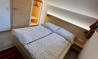 A cozy bedroom with a double bed and wooden-colored furniture. The room is bright and modernly furnished.