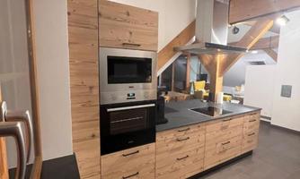 A modern kitchen with wooden cabinets and elegant appliances. The space has a bright and inviting atmosphere.