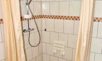 A modern shower with bright tiles and a shower curtain. The floor is designed with small, colorful tiles.